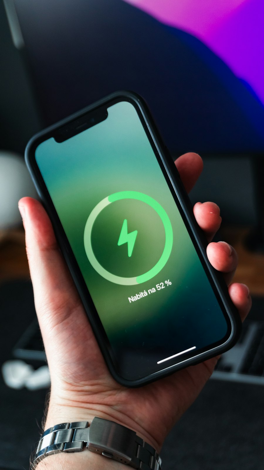 Hand holding an iPhone showing the charging screen