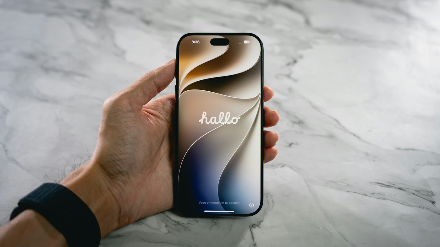 Hand holding a new iPhone showing the hello setup screen