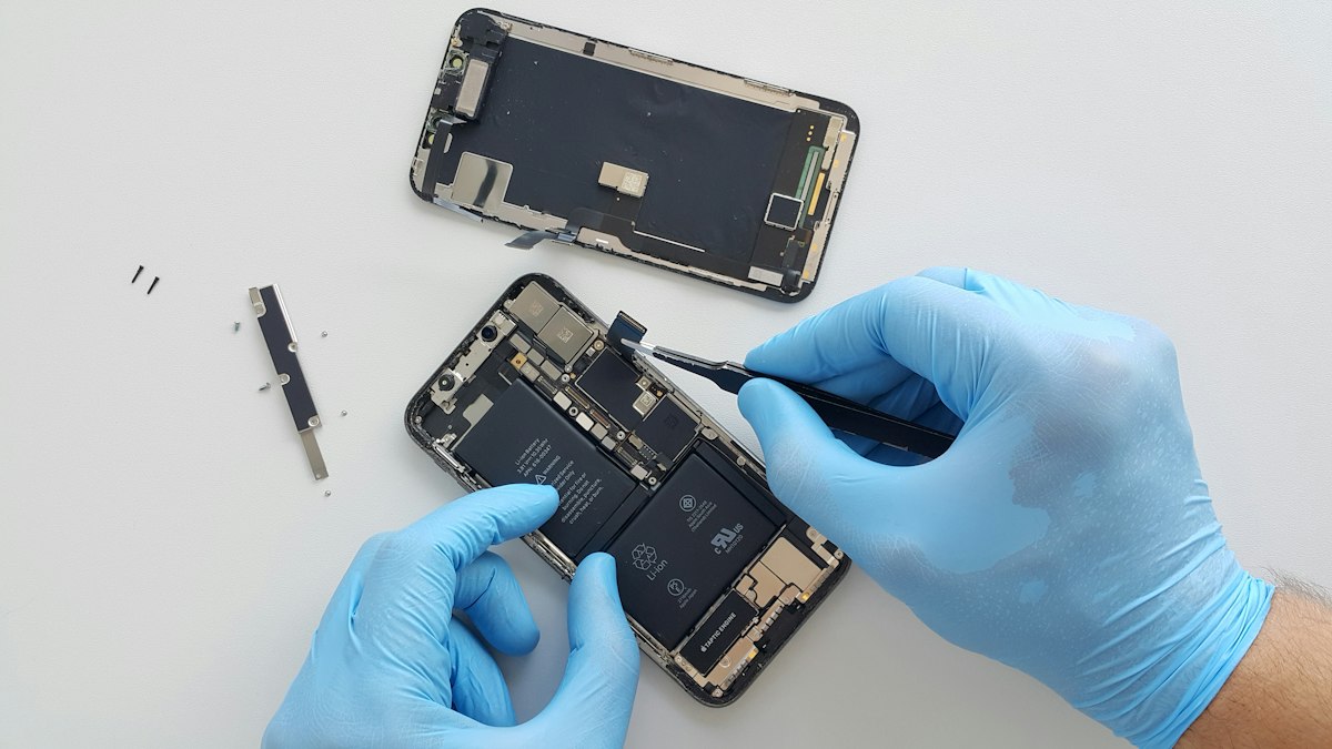 Technician in blue gloves repairing an opened iPhone